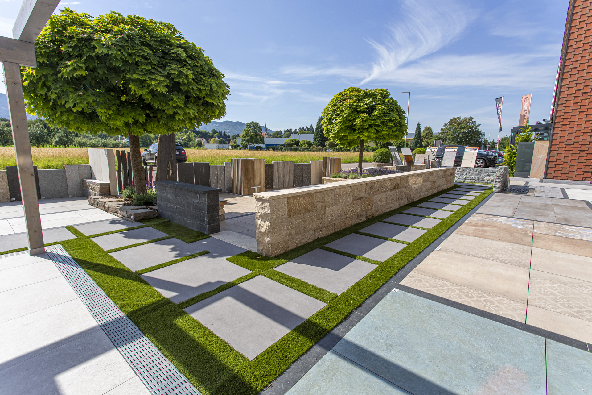 Gartenanlage mit Natursteinmauer, Bäumen und Plattenweg